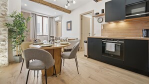 Una cucina moderna con forno integrato, un'area pranzo con un tavolo rotondo e sedie, e un'ampia pianta in vaso.