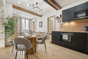 A modern kitchen with a built-in oven, a dining area with a round table and chairs, and a large potted plant. - L'Atelier des Remparts - Au cœur du Vieil Antibes (Antibes)