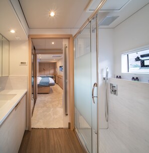 Ein schmaler Flur führt zu einem Schlafzimmer mit einem Bett, einem Badezimmer mit Dusche und einem Fenster mit Blick.
