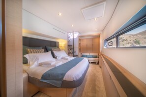 Ein Schlafzimmer mit Bett, Nachttischen, einem Fenster mit Blick und integrierten Stauraumlösungen.