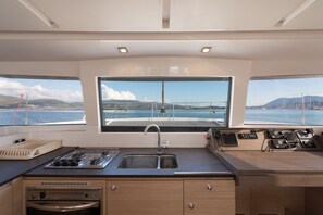 A kitchen with a large window, a stove, a sink, and a control panel. - Sun-Kissed Sailing Adventure in the Ionian Islands, Lefkada (Lefkada)