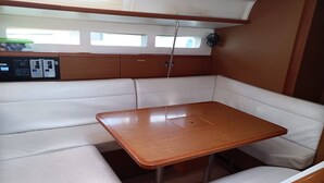 Un intérieur de bateau compact comprenant une table en bois, des sièges rembourrés et un panneau de commande.