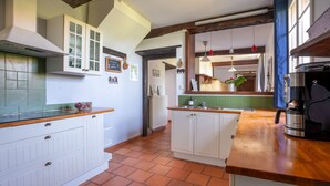 Cocina con alacenas blancas, encimera de madera y piso de baldosas.