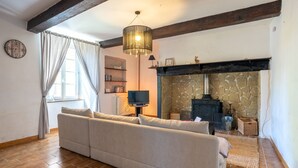 Una sala de estar con un sofá, una chimenea, un reloj y un televisor.