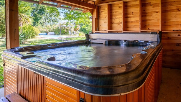 Un espacio tipo spa de madera con una bañera de hidromasaje, paredes de madera y vistas al exterior.