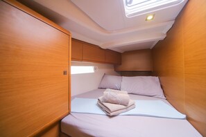 Ein kleines, helles Blockhäuschen mit einem Einzelbett, einem kleinen Fenster und Holzwänden.