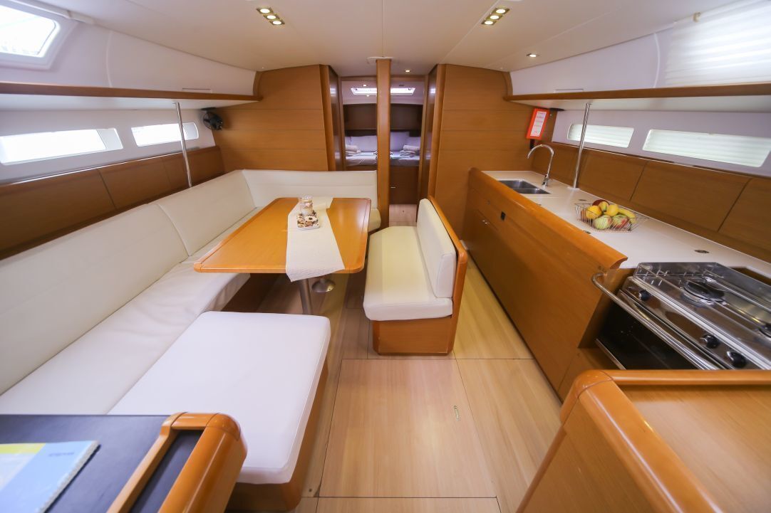 A compact galley with a dining table, bench seating, a stove, and a small sink.