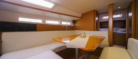 A compact, well-lit interior with a wooden table, cushioned seating, and built-in storage.