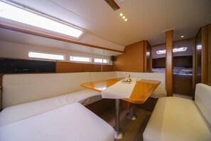 Um espaço interior compacto e bem iluminado, com mesa de madeira, assentos acolchoados e espaço de armazenamento embutido.