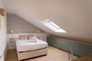 Ein Schlafzimmer mit Dachfenster, einem Bett, einem Nachttisch und einem grünen Schrank.