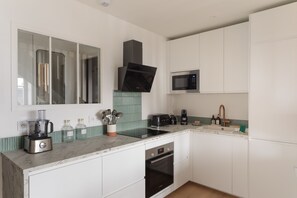Eine moderne Küche mit weißen Schränken, einer eingebauten Mikrowelle, einem Toaster und einer Kaffeemaschine.