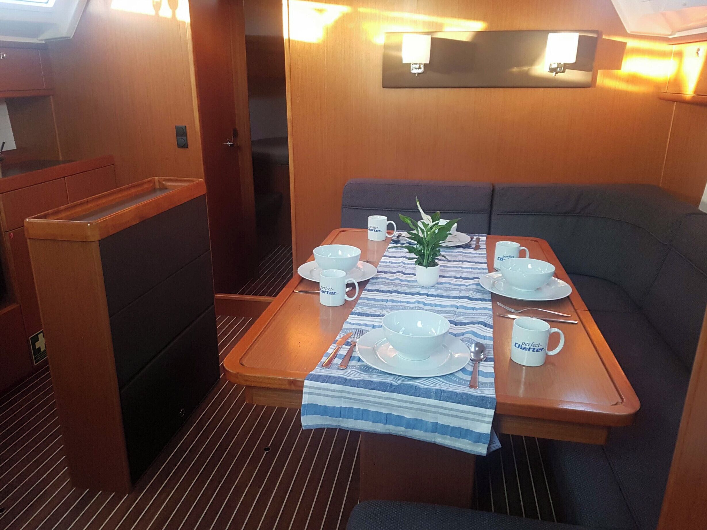Un comedor con una mesa preparada para dos, una planta pequeña en maceta y una lámpara de pared.