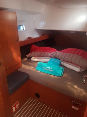 Uma cama beliche compacta com armário de armazenamento, um pequeno espaço para sentar e uma janela com vista.
