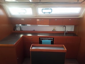 A compact kitchen with a built-in dishwasher, a sink, and a window above the countertop.