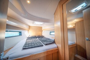 A compact, well-lit interior with a bed, skylight, and wooden cabinetry.