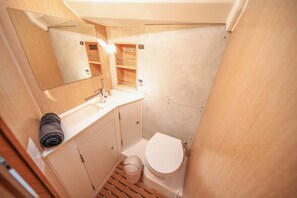 A compact bathroom with a sink, mirror, and toilet.