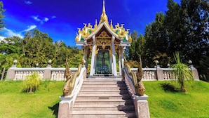 Un templo con una escalera que conduce a una entrada de techo dorado, rodeado de vegetación.