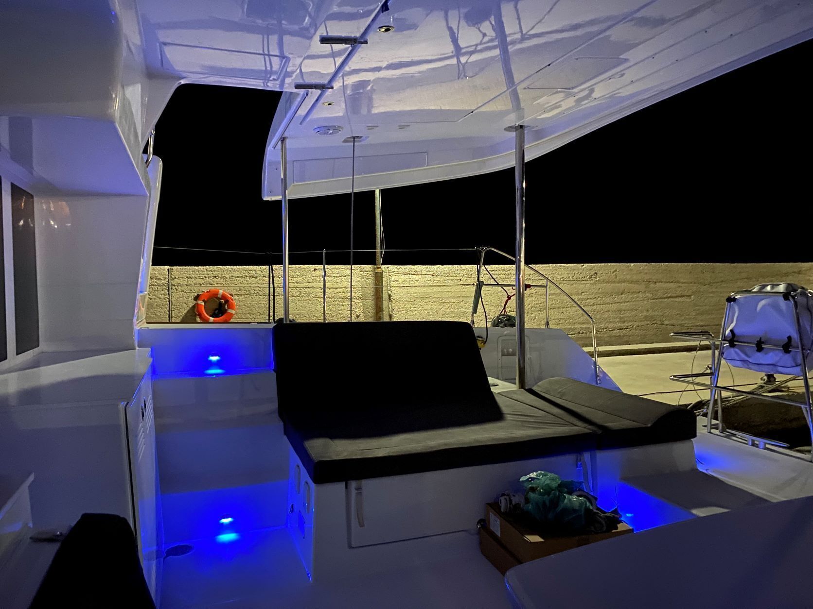 L'intérieur d'un bateau, avec un espace salon, un gilet de sauvetage et un pont éclairé de lumière bleue.