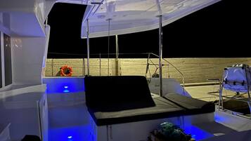 L'intérieur d'un bateau, avec un espace salon, un gilet de sauvetage et un pont éclairé de lumière bleue.
