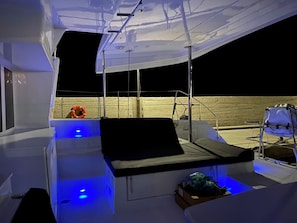 L'intérieur d'un bateau, avec un espace salon, un gilet de sauvetage et un pont éclairé de lumière bleue.