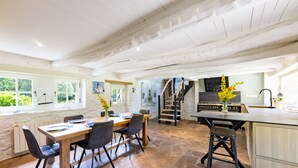 Una cocina amplia con comedor, piso de piedra y una escalera que sube a un nivel superior.