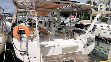 A boat deck with a seating area, a lifebuoy, and a small table.