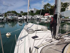 Ein Yachthafen mit vertäuten Booten, bewölkter Himmel und ein Gebäude im Hintergrund mit der Beschriftung 'ATSMA'.