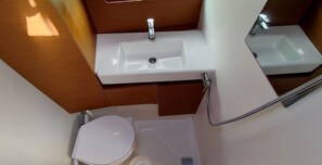 Une petite salle de bain avec un lavabo blanc, des toilettes et une douche.