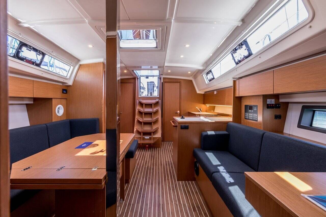 A compact interior with a dining area, seating, a small kitchen, and a central aisle.