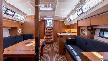 A compact interior with a dining area, seating, a small kitchen, and a central aisle.