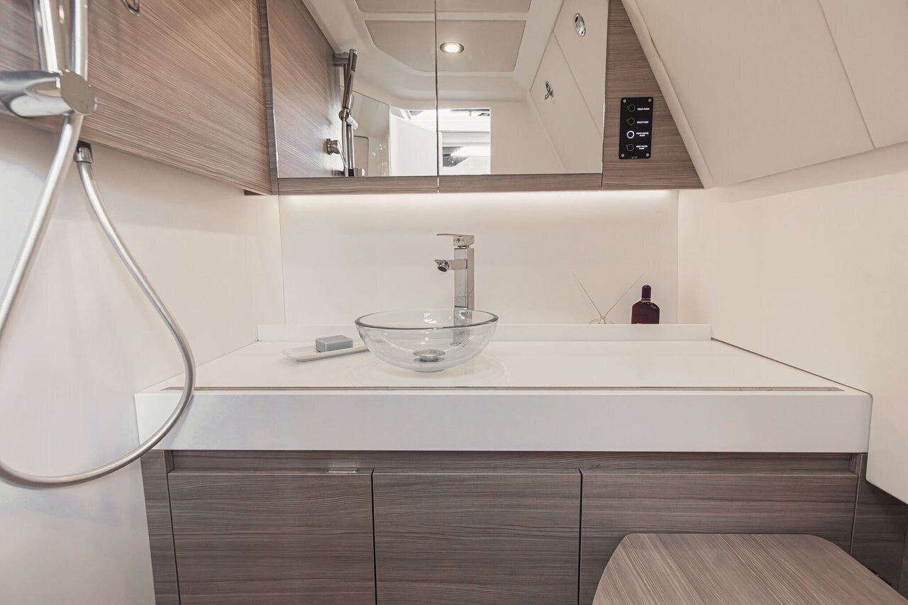 A modern bathroom with a glass bowl sink, a handheld showerhead, and a mirror above the sink.