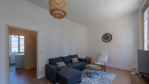 Una sala de estar moderna con un sofá modular, una mesa de centro, un mueble para la televisión, una lámpara de mimbre y un reloj en la pared.