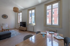 Ein modernes Wohnzimmer mit einem Holzesstisch, einem Fernseher und einem großen Fenster.