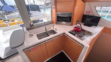 Una cocina pequeña y funcional con un lavabo, estufa, horno y un televisor.
