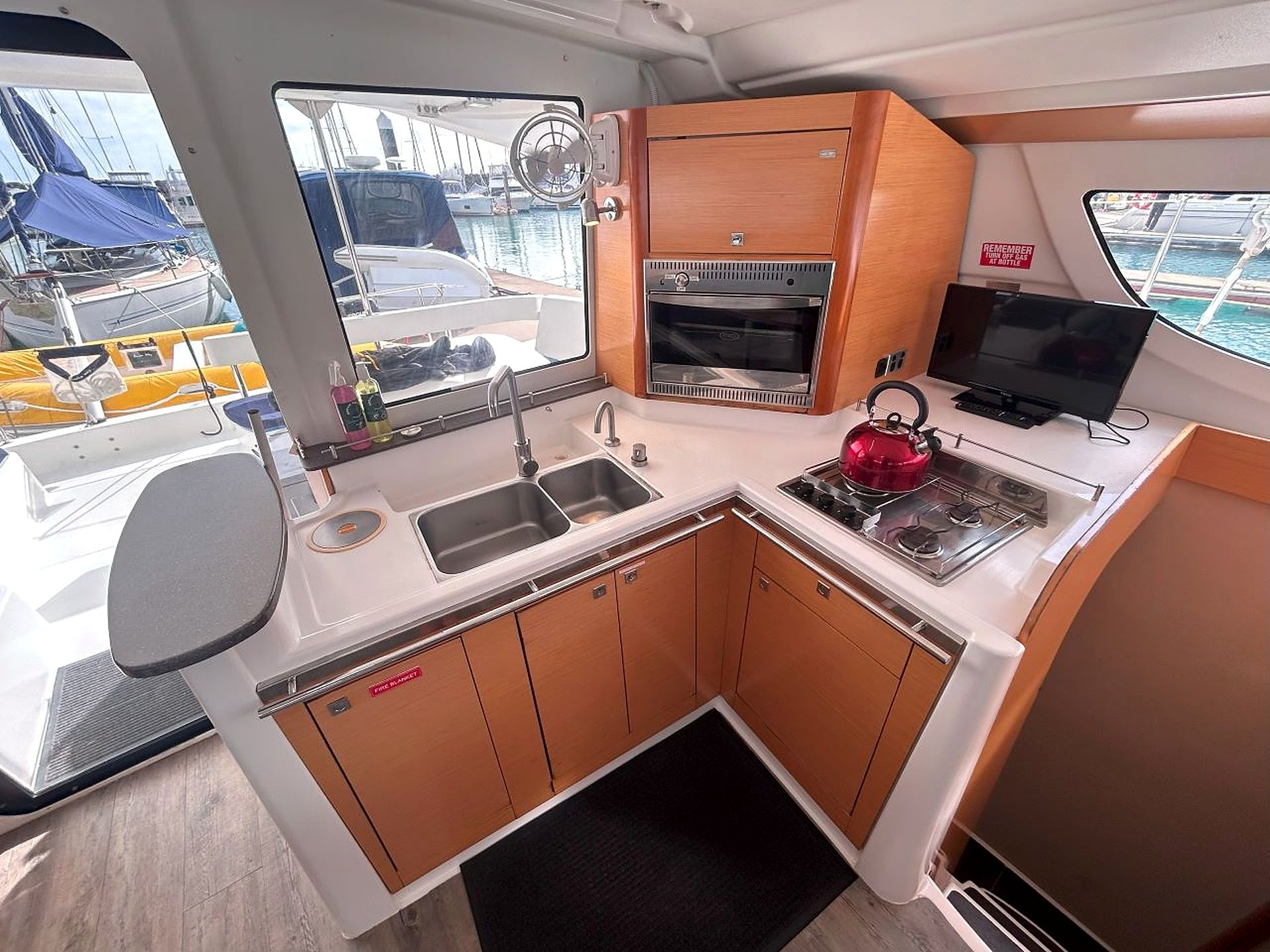 A compact galley kitchen with a sink, stove, oven, and a small television.