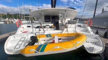 A boat with a yellow inflatable dinghy, a cabin, and a helipad.