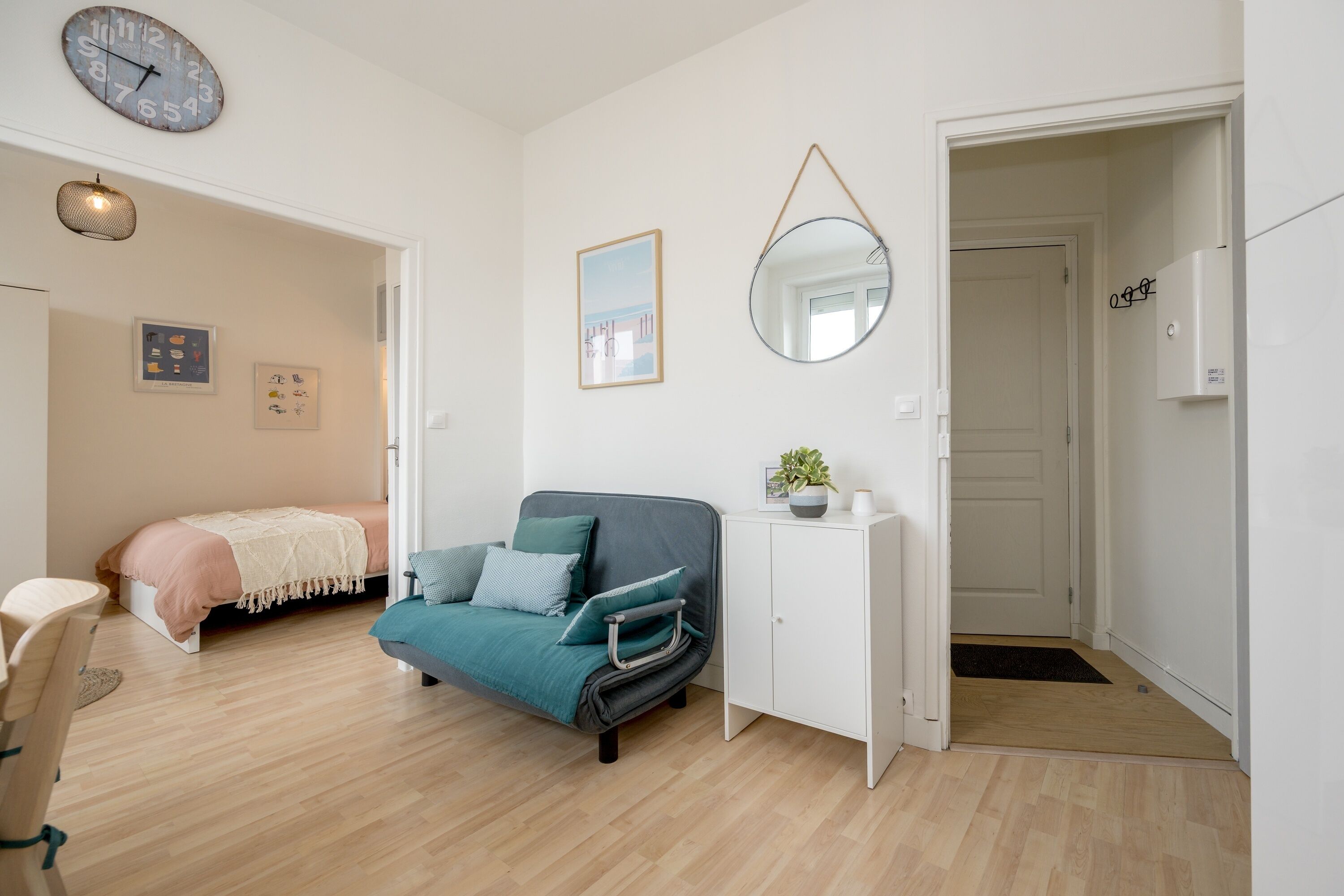 Et moderne soveværelse med seng, sofa, skrivebord, spejl og en dør.