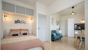 Ein Schlafzimmer mit Bett, einer Couch, einem Essbereich und einer Küche.