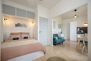 A bedroom with a bed, a sofa, a dining area, and a kitchen. - Le Studio du Val - 2min à pied de la plage (Pléneuf-Val-André)