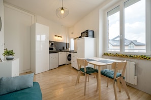 A modern kitchen with a dining table, chairs, and a view of the outside. - Le Studio du Val - 2min à pied de la plage (Pléneuf-Val-André)