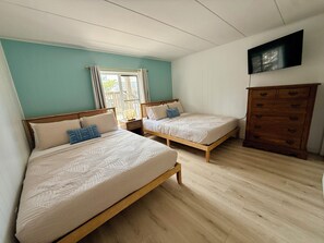 Een kamer met twee houten bedden, een houten dressoir en een televisie aan de muur.