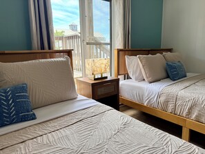 Two beds with headboards, a nightstand with a lamp, and a window with a view of buildings. - Oceanside Condo - Sleeps 6 - Beach Gear - Parking (Ocean City)