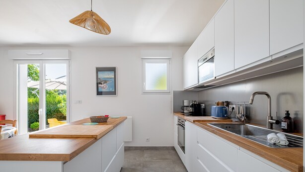 A modern kitchen with white cabinets, a wooden countertop, and a built-in oven. - Guilvin - Charmante maison à 2 pas du port (Locmariaquer)