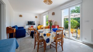 A spacious living area with a dining table, chairs, a sofa, and a television. - Guilvin - Charmante maison à 2 pas du port (Locmariaquer)