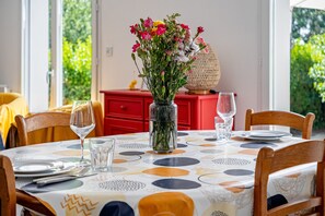 A dining table with a vase of flowers, plates, and glasses. - Guilvin - Charmante maison à 2 pas du port (Locmariaquer)