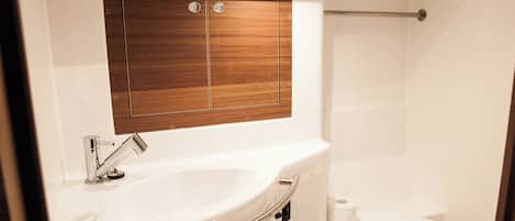 A compact bathroom with a white sink, wooden vanity, and a toilet.