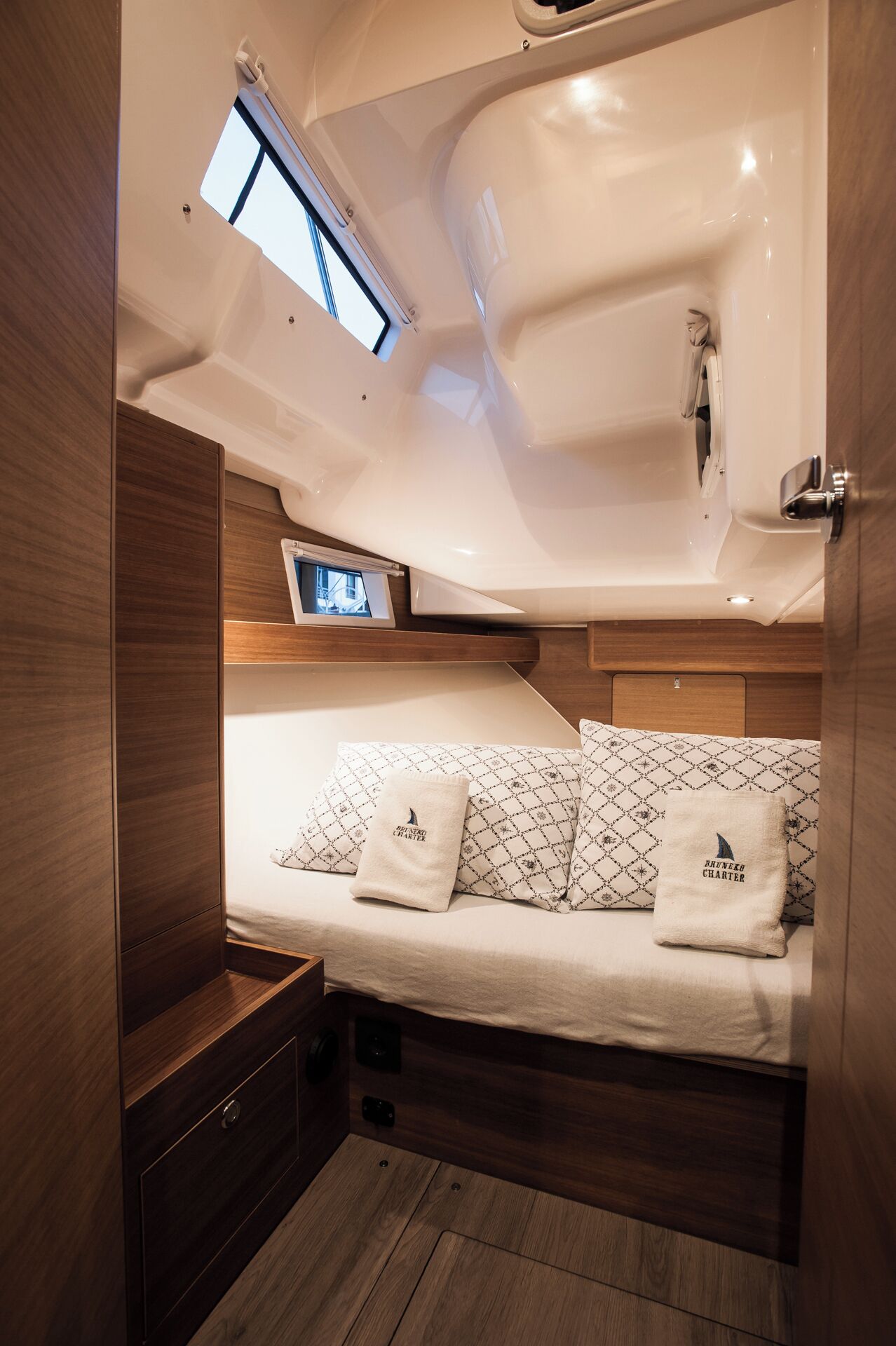 A compact cabin with a bed, a small window, and a built-in TV.