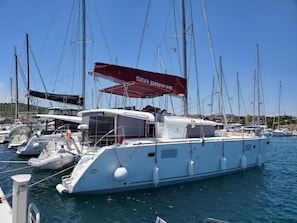 En småbåtshamn med flera yachter förtöjda, inklusive en stor vit yacht med ett rött kapell där det står ”SEA BREEZE”.