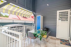 A covered outdoor seating area with a table and chairs, a car parked nearby, and a blue cabinet. - L'Etoile des îles - À moins d'1 km de la plage (Sainte-Anne)