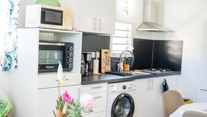 Una cucina compatta con microonde, forno, tostapane, lavello e lavatrice.